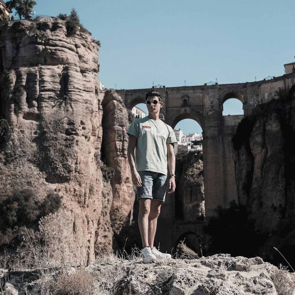 man in grey T-shirt stands on rock