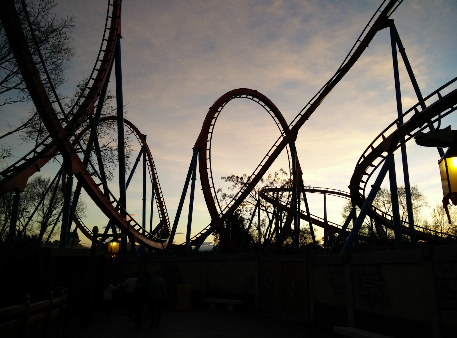 A roller coaster climbing its lift hill at a theme park during golden hour