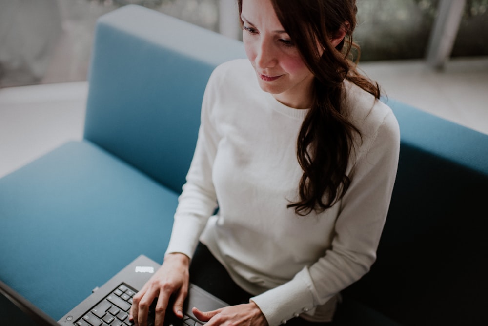 woman sitting on sofa while surfing on laptop