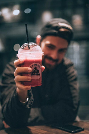 A smiling customer holding a smoothie cup with the oroviva logo in a cozy café setting.