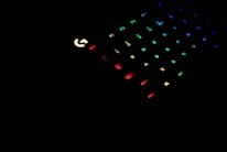 A dark setting with a partially visible gaming keyboard. The keys are illuminated with various colors including red, green, blue, and yellow, adding a vibrant contrast against the black background.