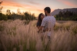 An intimate moment between a couple during golden hour, framed by soft country landscape hues.