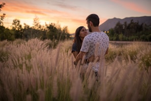 An intimate moment between a couple during golden hour, framed by soft country landscape hues.