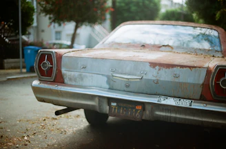 A weathered but sturdy old sedan parked on a quiet Bronx street, ready for donation.