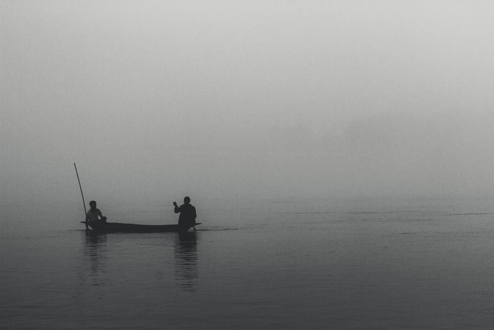silhouetted of two persons riding on boat