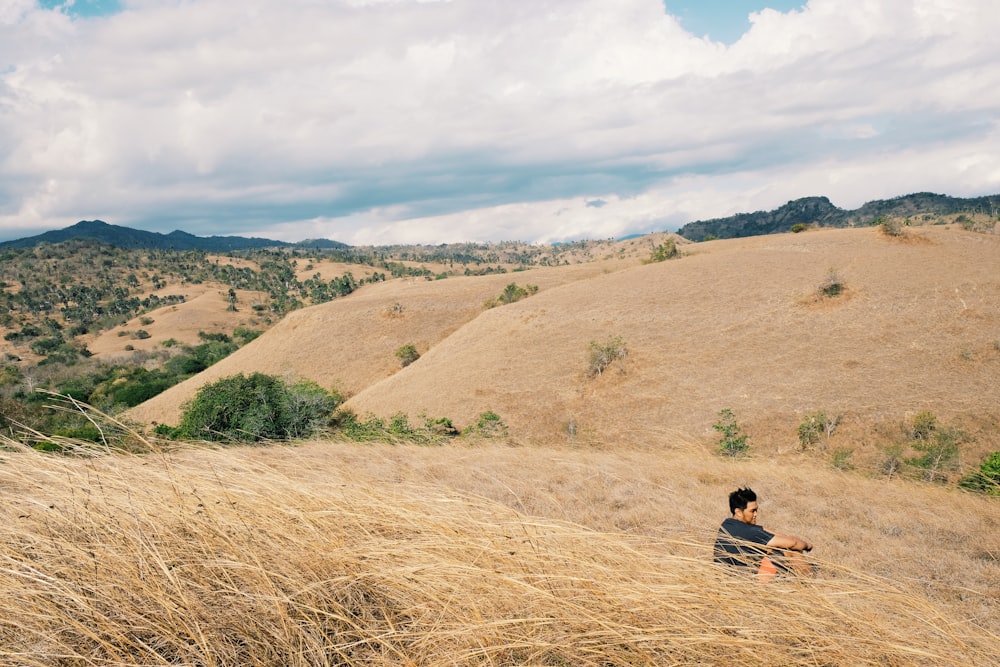 man sitting on hay during daytime