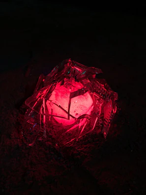 A close-up of a mysterious artifact glowing with red-orange hues in a dark environment.