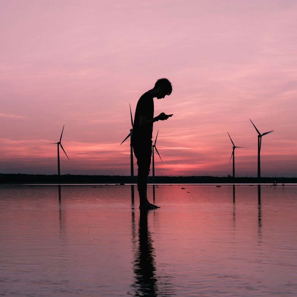 silhouette photography of man standing while using smartphone