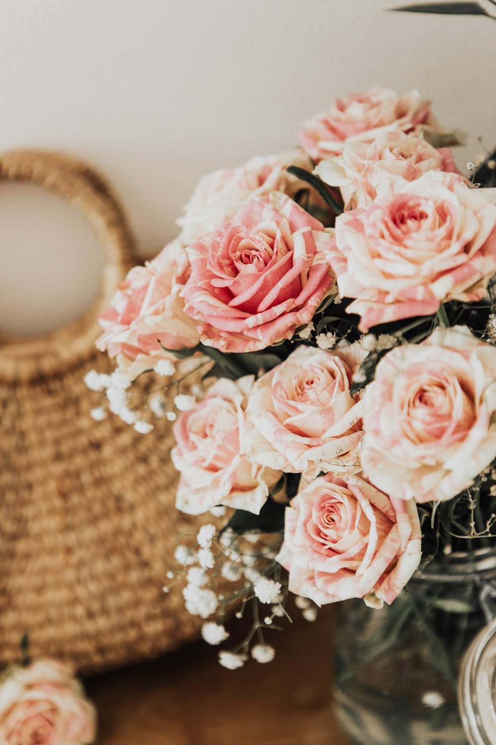 pink rose flower centerpiece beside brown handbag