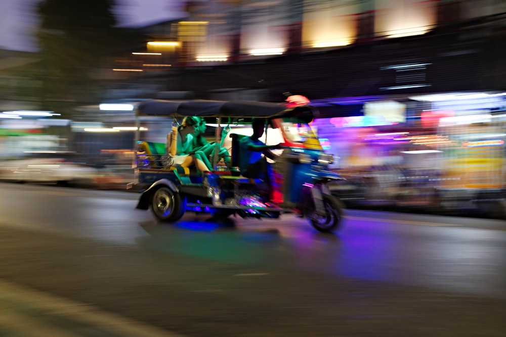 people rides tuk-tuk in lighted city street