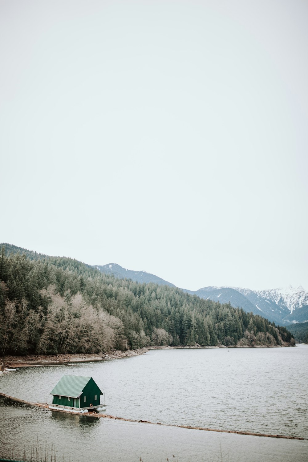 green house by the beach and mountains surrounded with trees