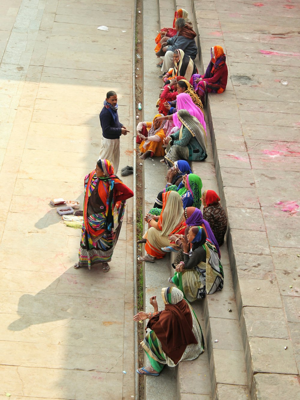 women wearing sari dress sitting on concrete stairs during daytime