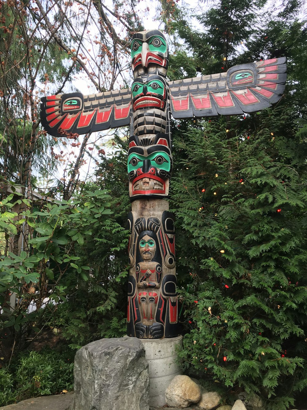 tiki mask statue beside green trees during daytime