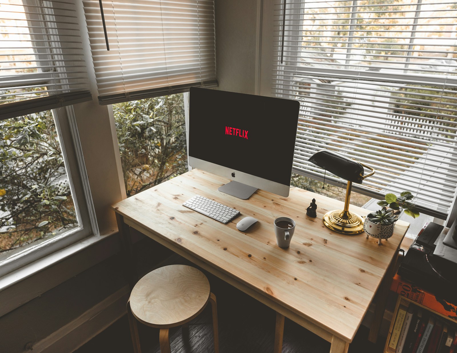 small apartment wood desk by window with imac task lamp and plant