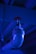 A close-up view of a metallic industrial pipe leading to a sprinkler or nozzle, illuminated by a blue light. The pipe has a shiny surface and connects to a red circular component mounted under a ceiling with a ribbed structure.