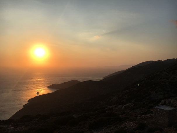 Sunset view where the sea meets the blue hills, casting golden hues over the landscape.