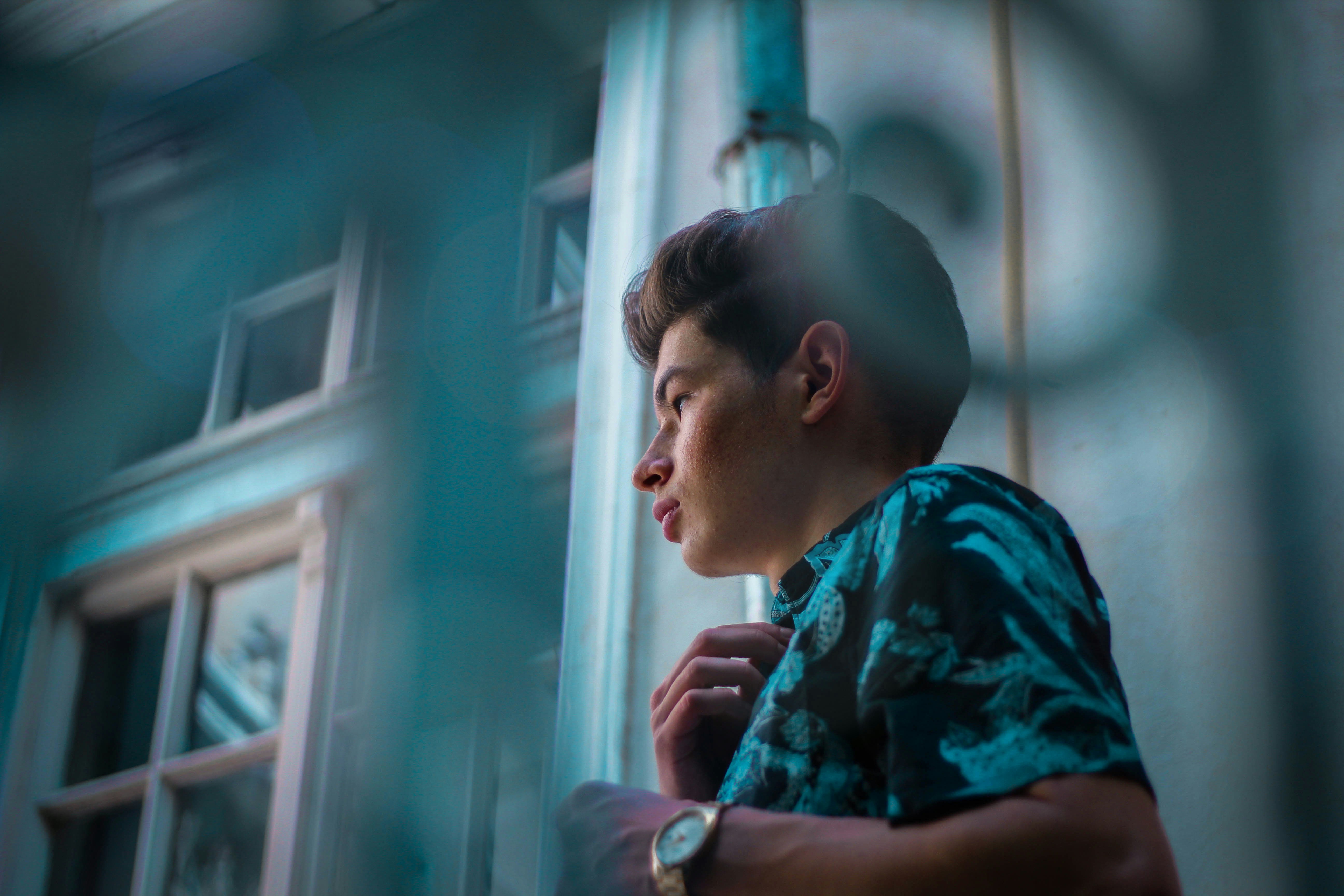 man in blue shirt standing beside building