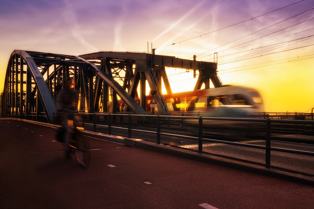 time-lapse photography of biker passing road beside trail during golden hour,