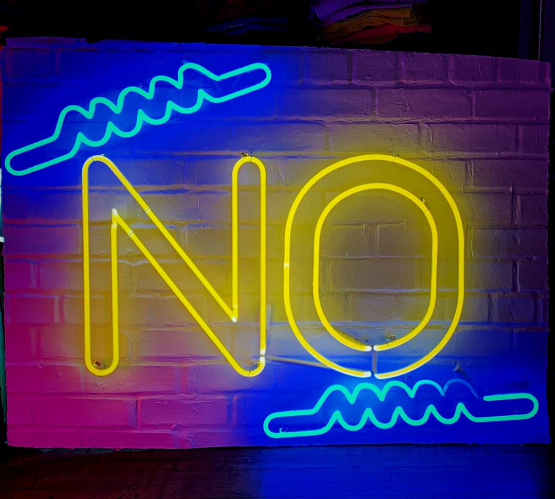 a neon sign on a brick wall that says no