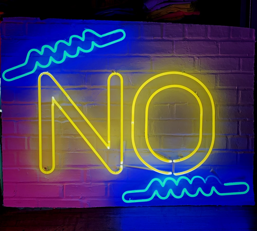 a neon sign on a brick wall that says no