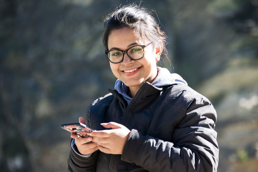 selective focus photography of smiling woman using smartphone