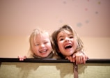 Two boys laughing while building a fort with blankets.