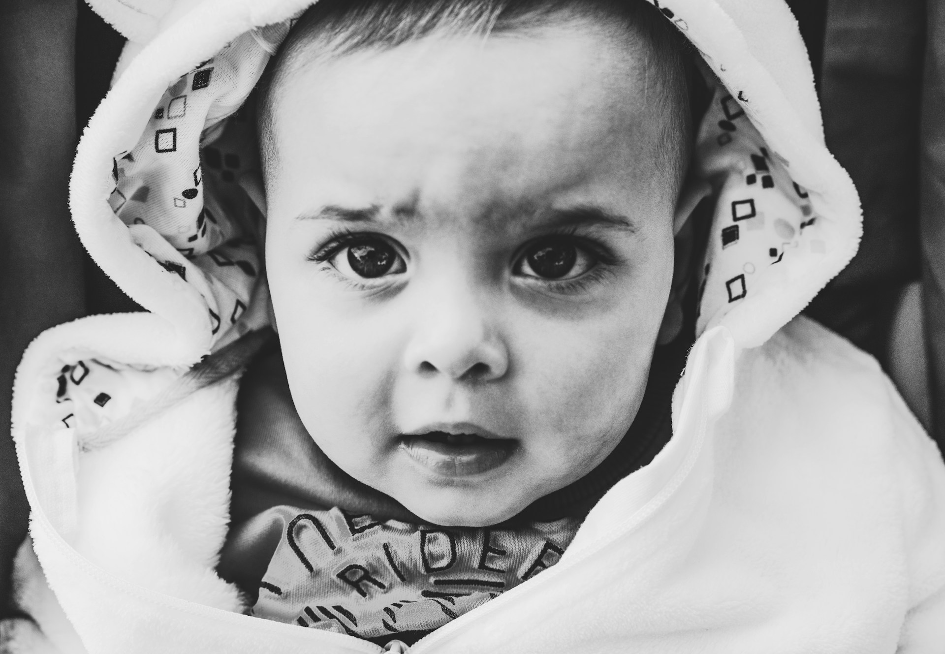 A close-up portrait of a smiling baby wrapped in a cozy blanket, highlighting delicate features and innocence.