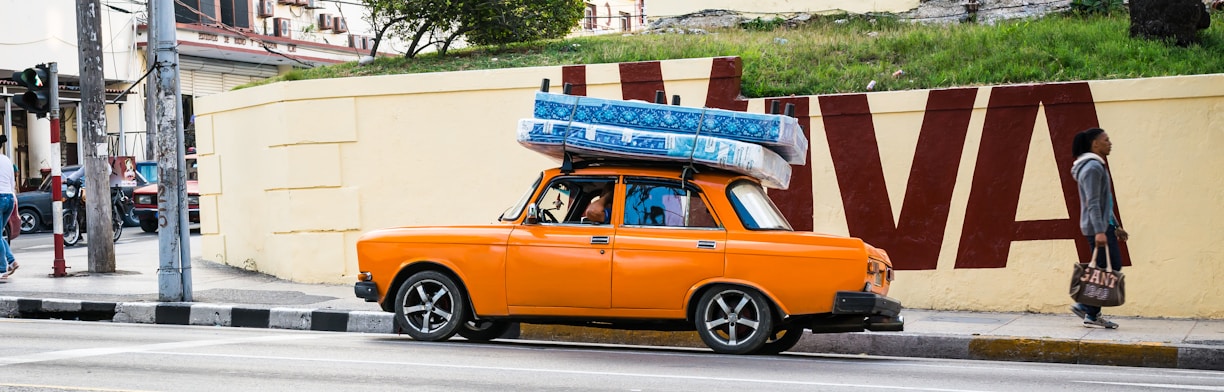 an orange car with a surfboard on top of it