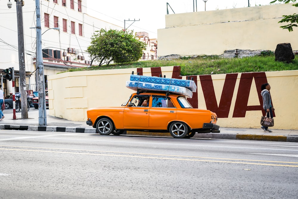 an orange car with a surfboard on top of it
