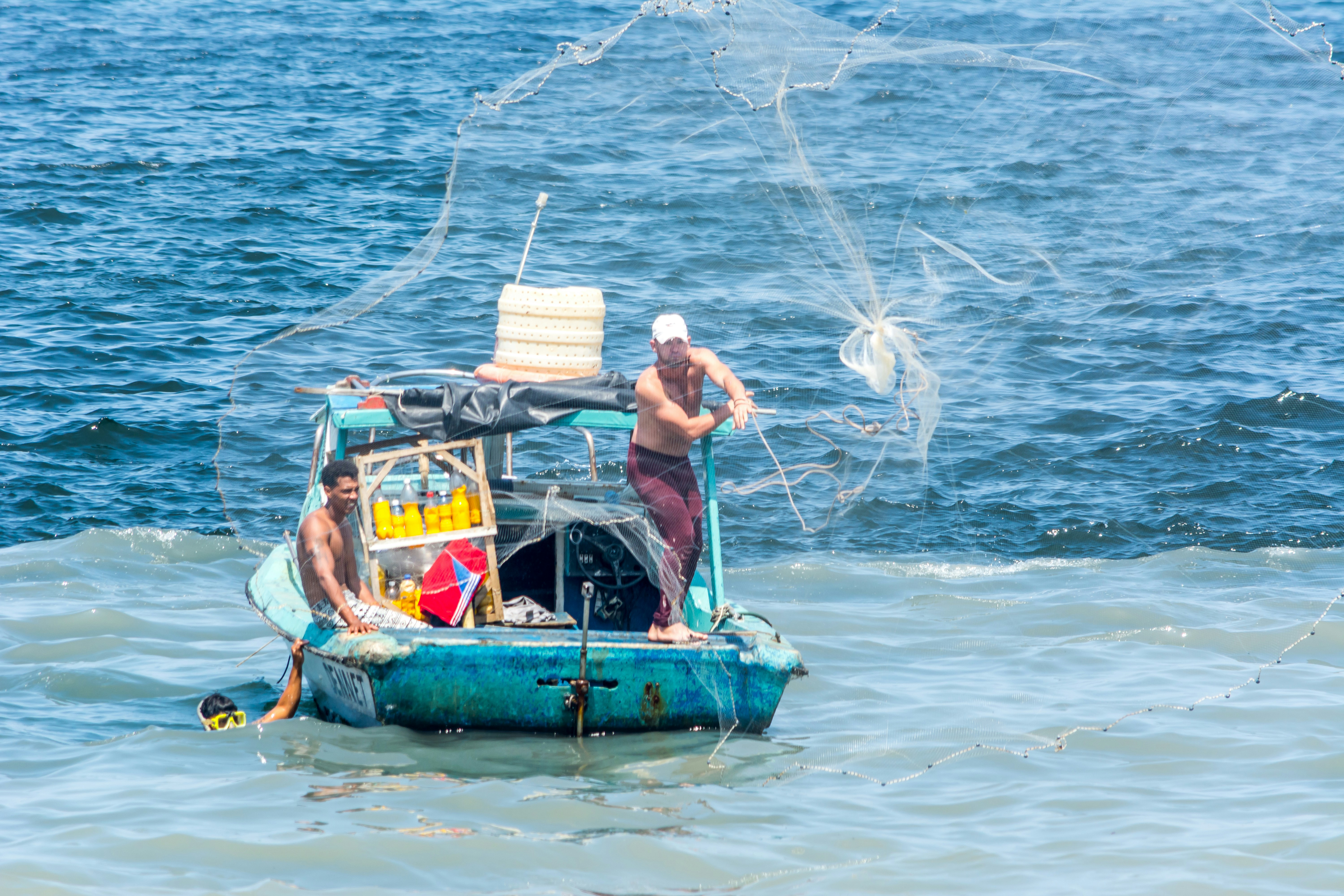 2 men in blue and yellow boat on body of water during daytime