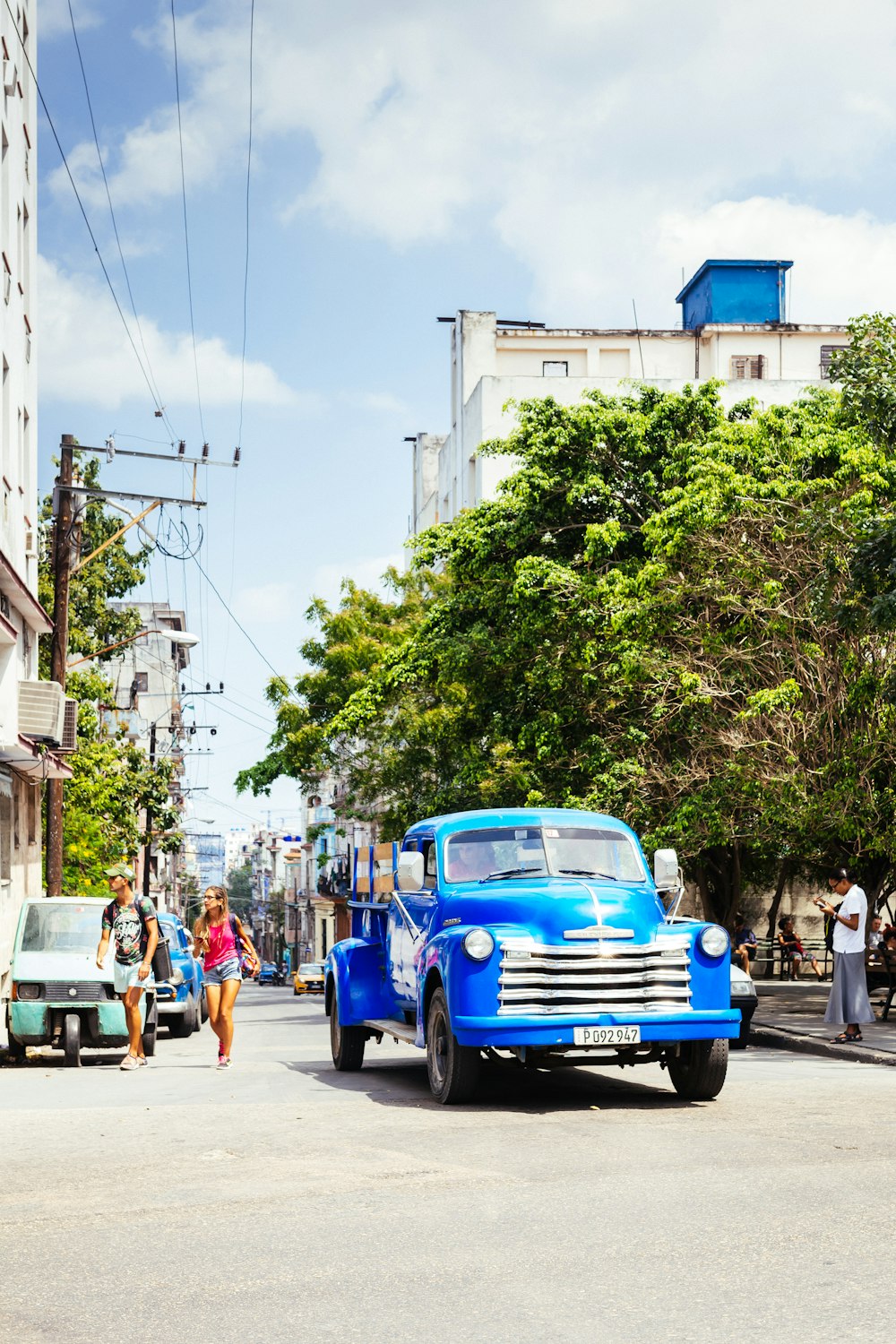 blue vehicle on road beside tree during daytime