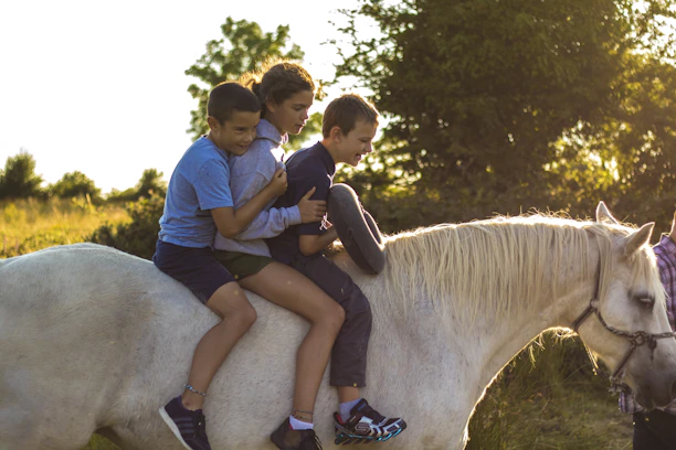 Group of children happily riding horses together during summer camp.