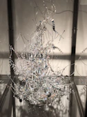 Abstract sculpture made of twisted metal reflecting light in a gallery space