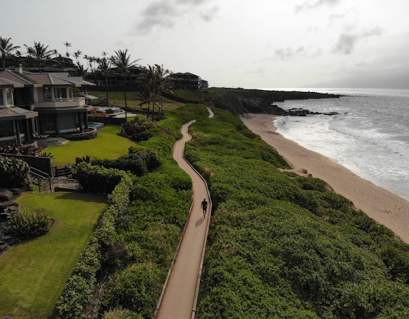 Scenic coastal path near a beachfront villa under a clear blue sky