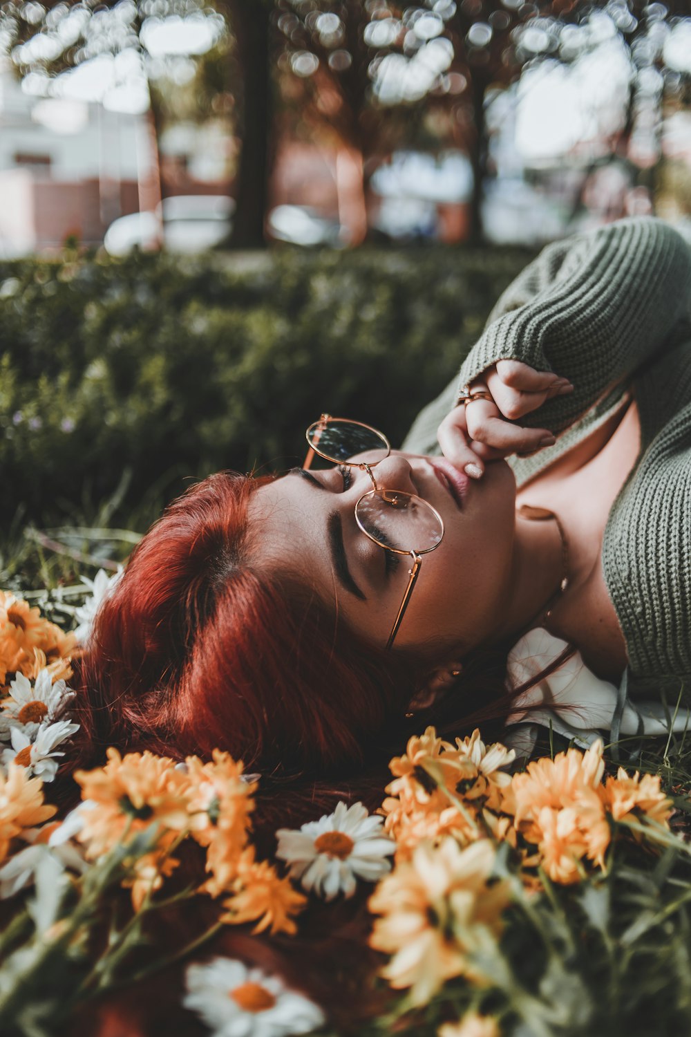 mulher deitada no canteiro de flores com a mão direita no queixo