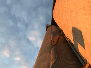 View of a large silo supported by deep continuous flight auger foundations on a sunny day.