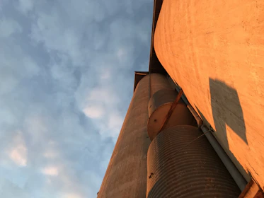 View of a large silo supported by deep continuous flight auger foundations on a sunny day.