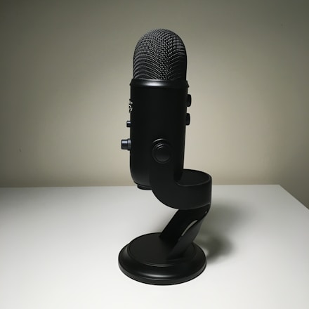 A sleek purple and black microphone glowing softly against a silver backdrop.