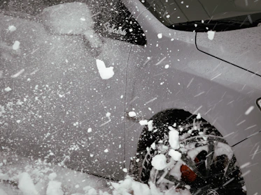 Illustration of a car under a snowflake with protective winter gear symbols.