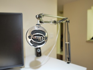 Close-up of a modern webcam and microphone on a light brown desk, with no people visible, highlighting simple, aesthetic gear.