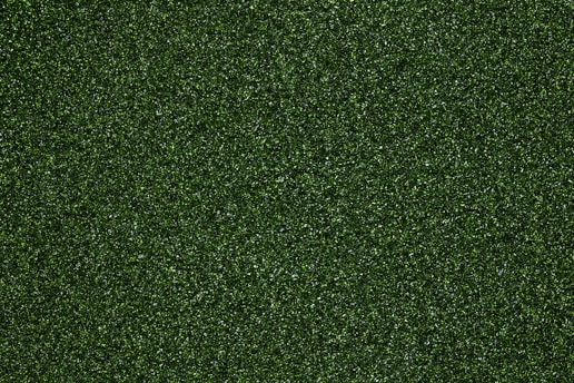 A dense pattern of dark green glitter, creating a textured and shimmering effect. The surface is evenly covered with small, reflective particles that catch light from various angles.