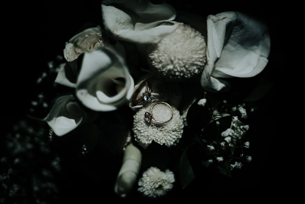 grayscale photo of flowers and ring
