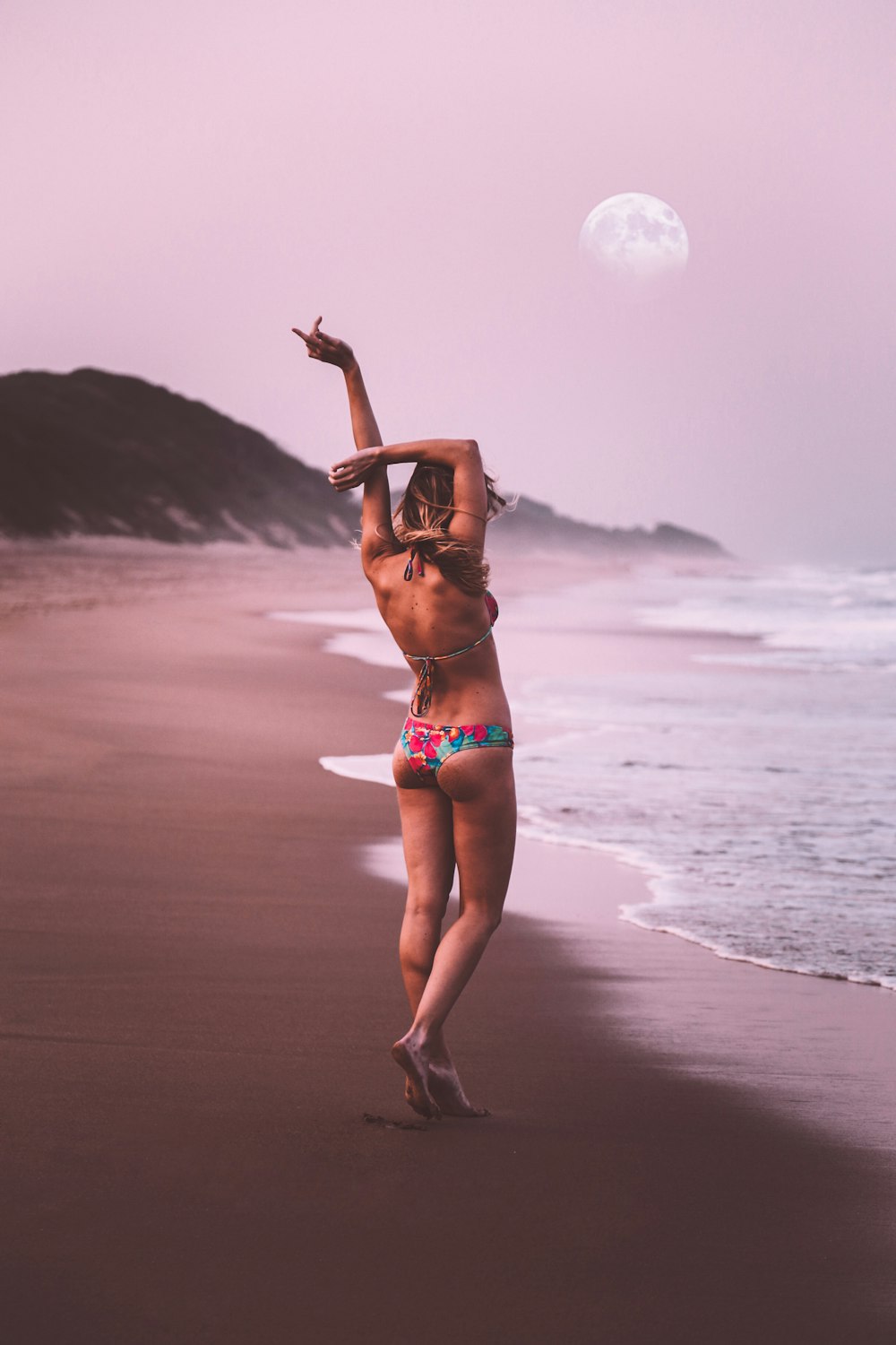 woman wearing multicolored swimsuit walking on seashore