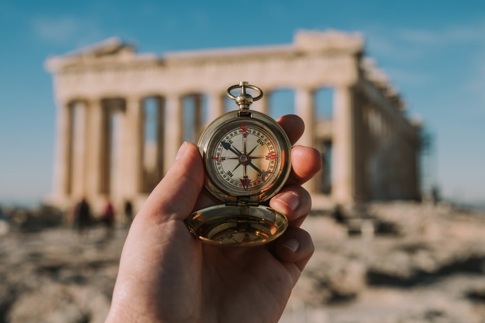 person holding gold-colored compass