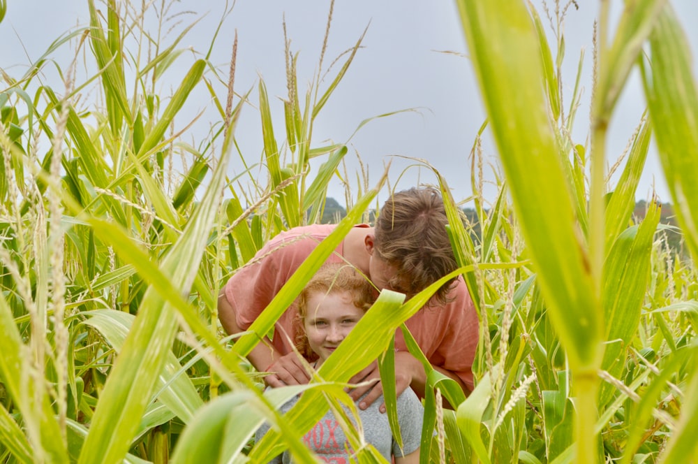 Il ragazzo tiene la spalla delle ragazze nel campo di grano
