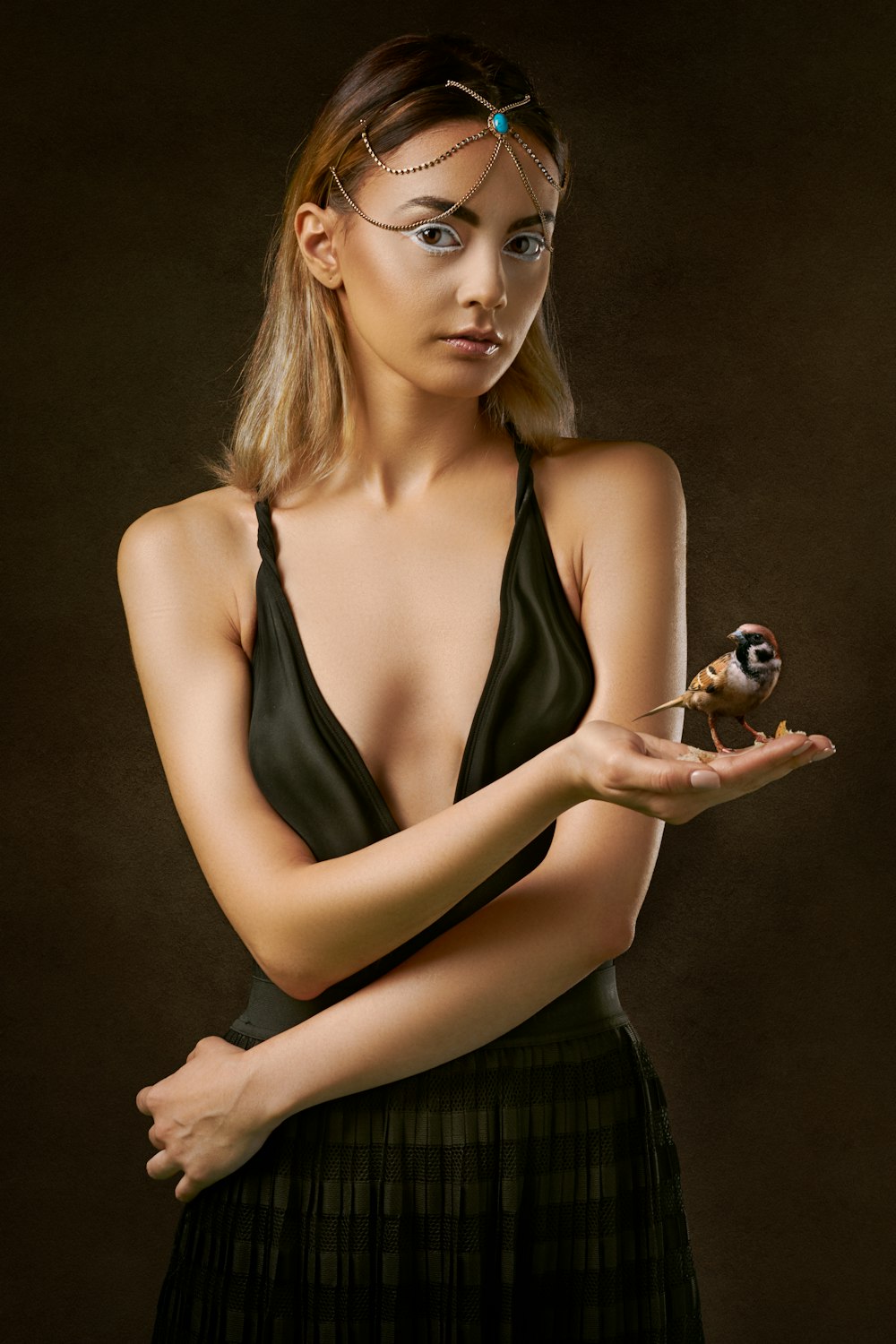 woman in black spaghetti strap dress holding brown bird