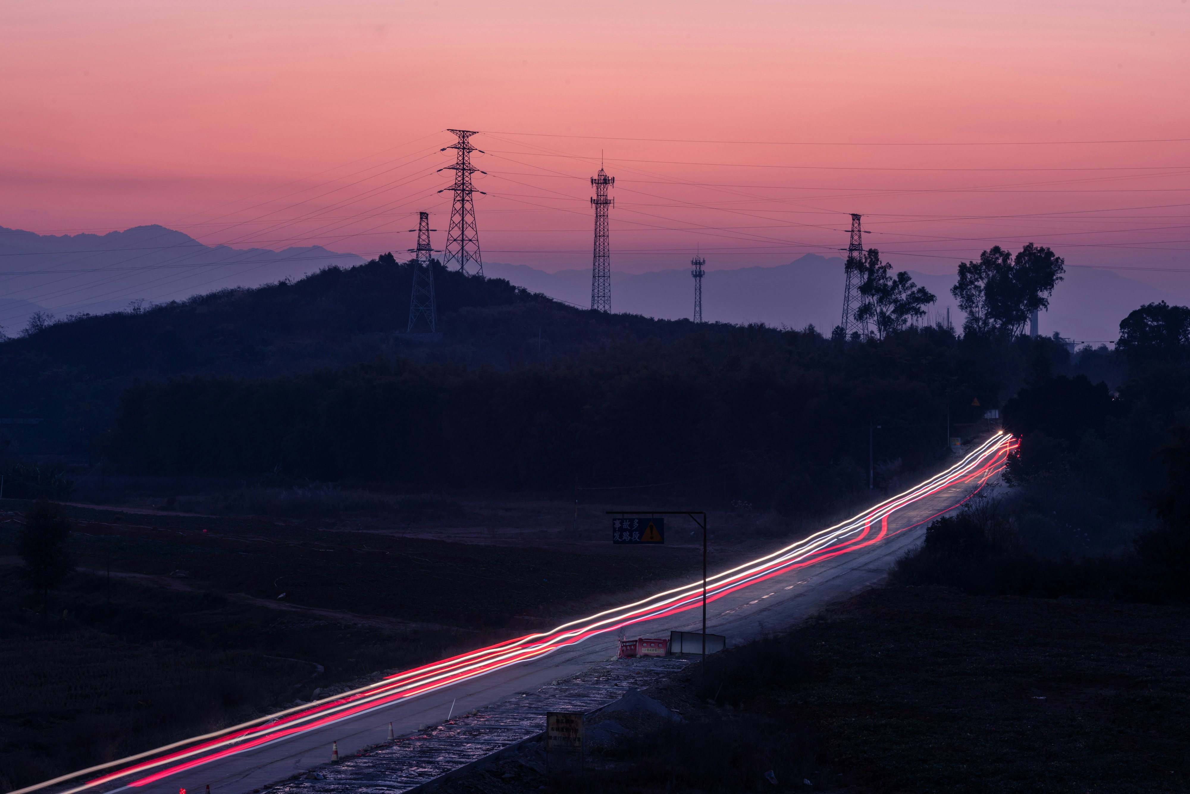Electric car driving on an open highway at sunset, illustrating real-world EV driving range