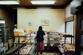 Friendly staff handing a freshly baked loaf to a smiling customer inside the cozy bakery.