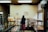 A smiling business owner standing inside a cozy bakery with shelves of fresh bread and pastries.