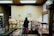 A smiling business owner standing inside a cozy bakery with shelves of fresh bread and pastries.